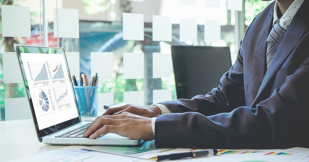 business person working on laptop seeing lower hiring costs from using a staffing agency