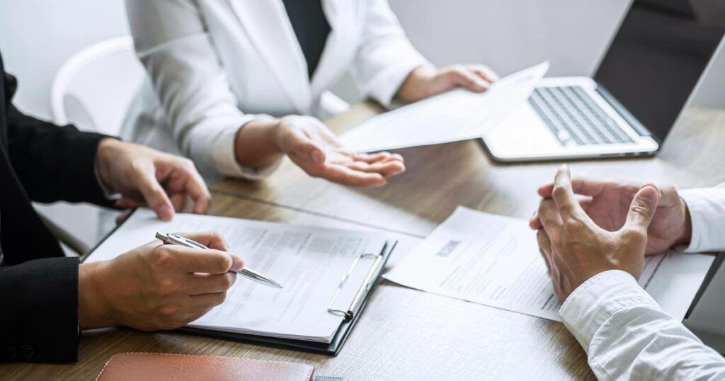 three coworkers reviewing multiple resumes