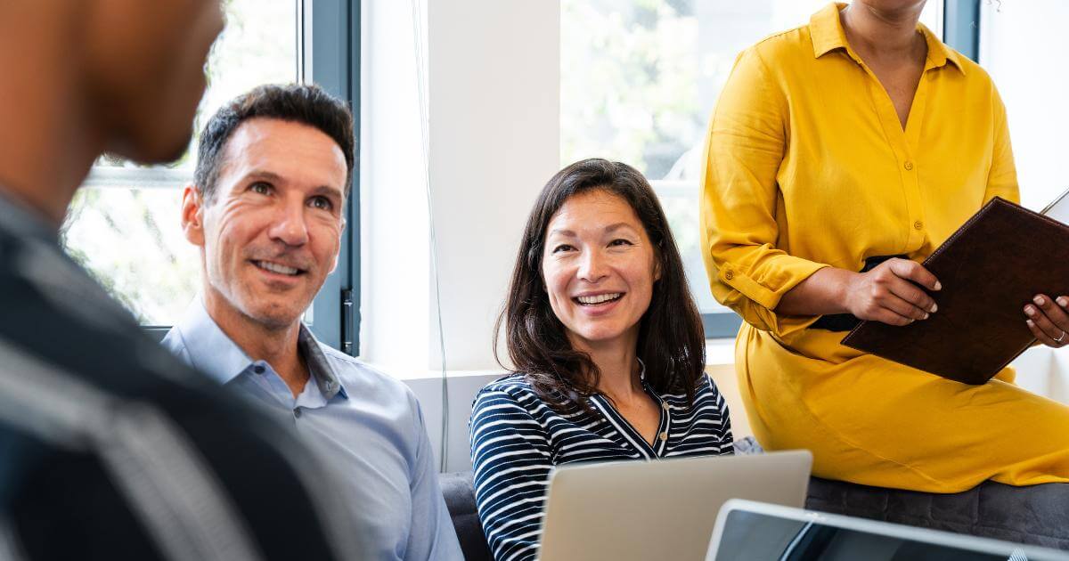 What Employers Really Gain from AI-Driven Staffing Support (1) HR professionals meeting together in an office, reviewing information on a laptop and discussing hiring decisions